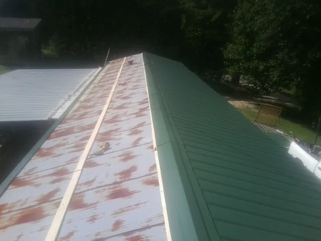 Old rusted panels beside newly installed green metal roofing — Wind Damage Roof Repair by Roofing Brothers in West Fargo
