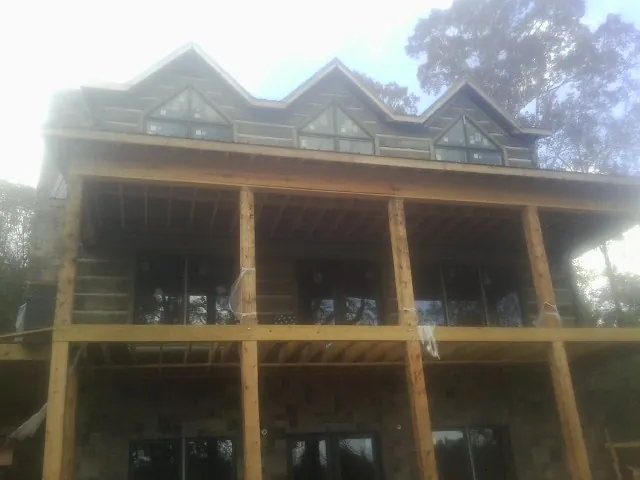 Dormers and porch framing on a large log home under construction — Roof Coating work by our crew in West Fargo