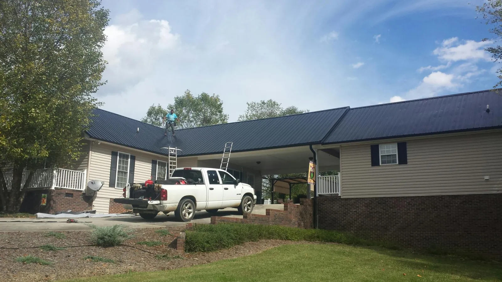 Black metal roof over a home and attached breezeway with ladders set in West Fargo