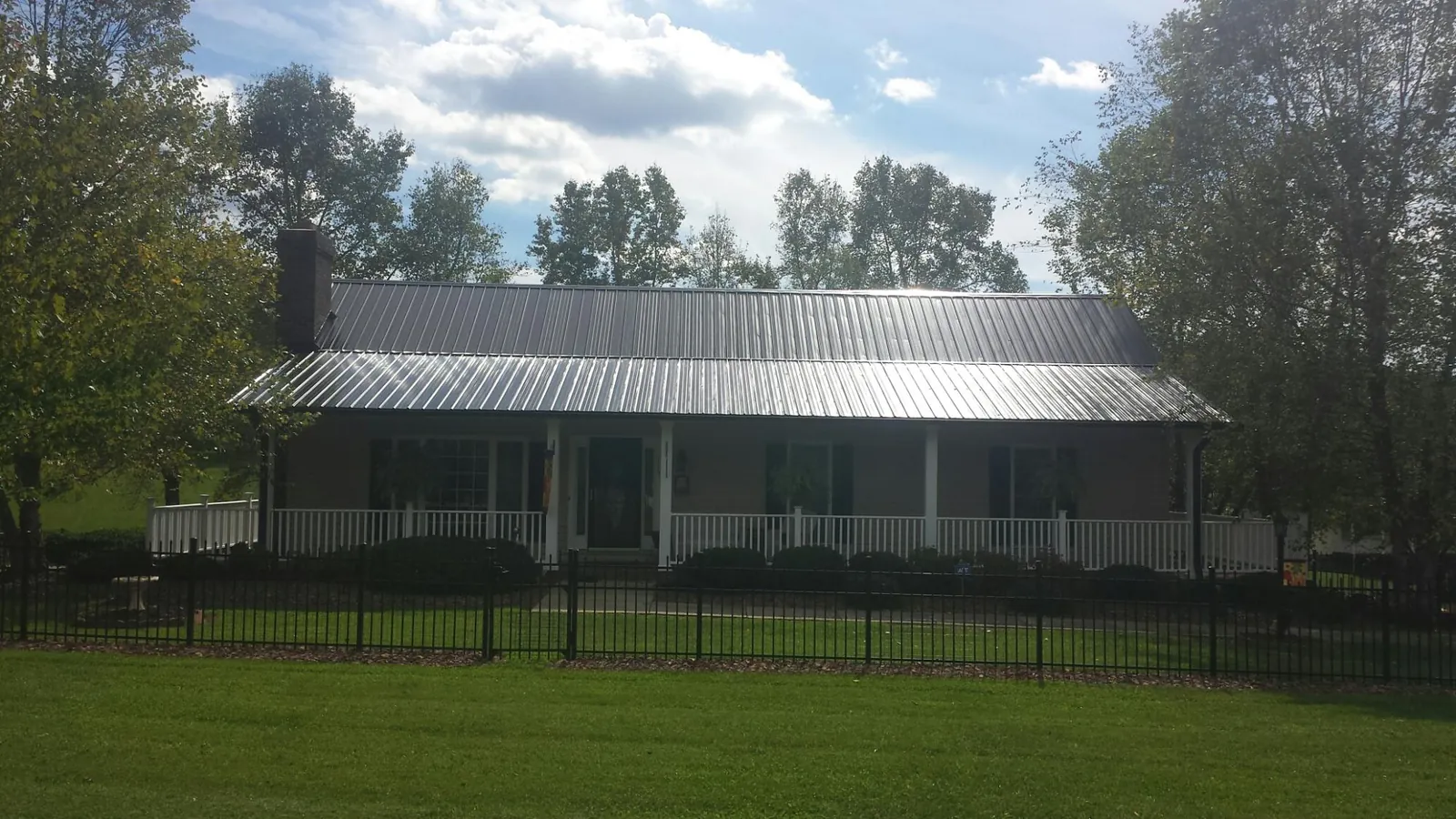Gray metal roof on a brick ranch with a full width front porch — Gutter Guard Installation work by our crew in West Fargo