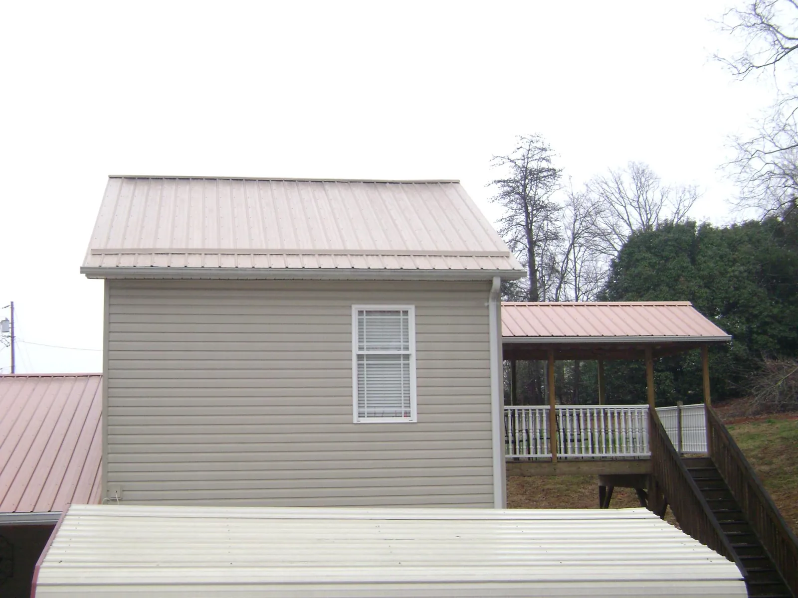 Tan metal roofs on a two story addition and attached porch, from a Roof Replacement job in West Fargo