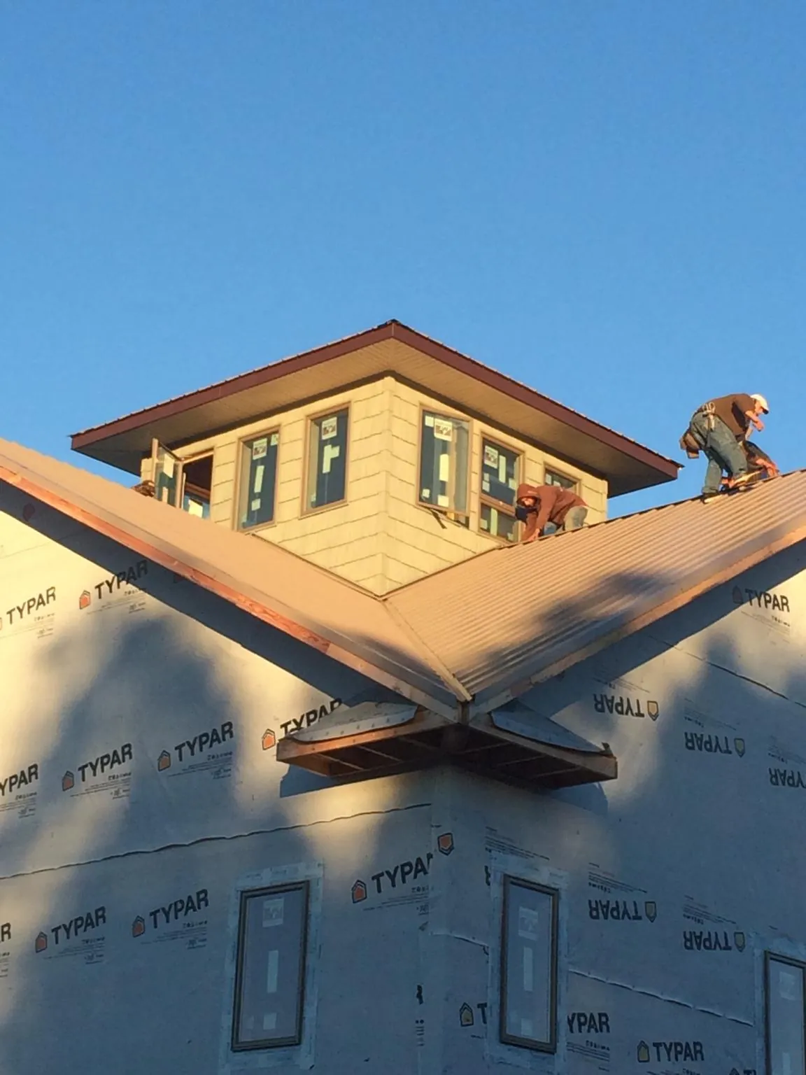 Roofers working around a rooftop cupola on a new metal roof at sunset — Roof Waterproofing in West Fargo by Roofing Brothers